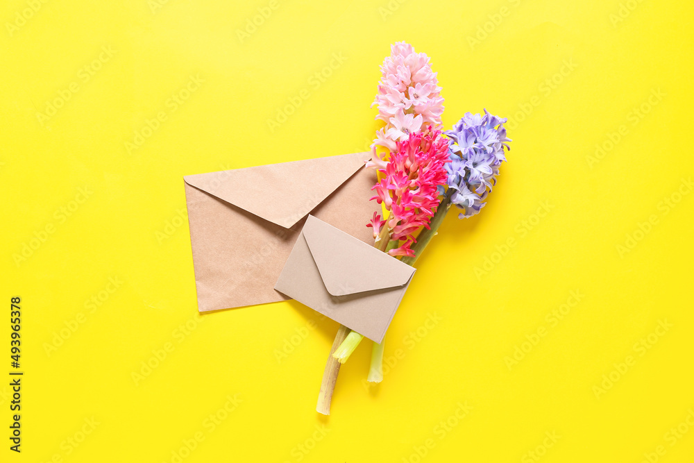 Envelopes and beautiful hyacinth flowers on yellow background