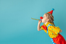 Funny Kid Clown Against Blue Background. Happy Child Playing With Festive Decor. Birthday And 1 April Fool's Day Concept