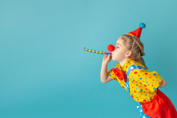 funny kid clown against blue background. happy child playing with festive decor. birthday and 1 apri