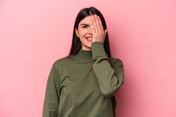 Wall Mural - Young caucasian woman isolated on pink background having fun covering half of face with palm.