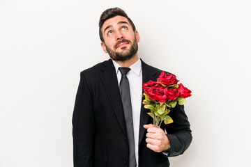 Wall Mural - Young caucasian man holding a bouquet of flowers isolated on white background dreaming of achieving goals and purposes