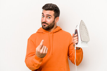 Young caucasian man holding an iron isolated on white background pointing with finger at you as if inviting come closer.