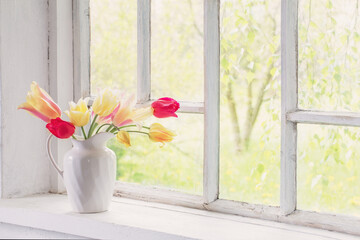 beautiful tulips in vase on white windowsill