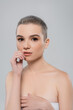 © LIGHTFIELD STUDIOS - pretty woman with short hair touching lips and looking at camera isolated on grey.