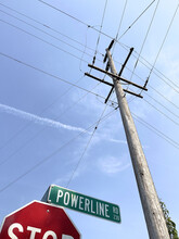 Low Angle Of A Utility Pole With Warning Sign And Wires Against Blue Sky