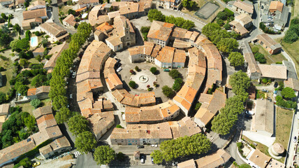 Wall Mural - Aerial shot of a medieval round village with red tile roofs surrounded by green fields and trees