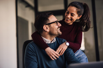 Wall Mural - People in love, smiling at each other while spending the day at the office.