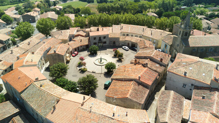 Wall Mural - Aerial shot of a medieval round village with red tile roofs surrounded by green fields and trees