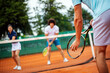 © NDABCREATIVITY - Tennis sport people concept. Mixed doubles player hitting tennis ball with partner standing near net