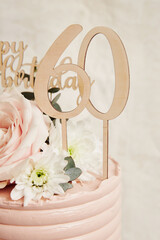 Poster - Vertical closeup of the decorations on a 60-year-old's birthday cake on a turntable,pink frosting