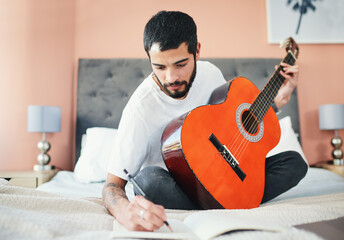 Aufkleber - Im sure this is going to be a hit. Shot of a man writing in his notebook while playing the guitar at home.