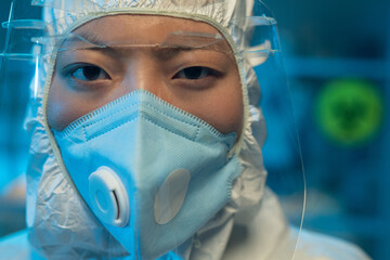 Aufkleber - Asian female chemist or healthcare worker in white biohazard suit, respirator and protective facial screen looking at camera