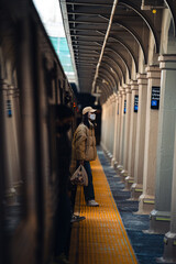 Poster - Closeup of a woman in a mask standing near a train