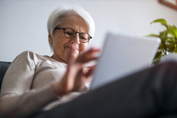 Wall Mural - Senior woman using a digital tablet at home
