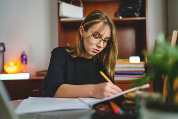 One young caucasian woman female student sitting at home writing in her notebook holding pencil while study preparing for exam learning and education concept real people copy space