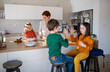 © Halfpoint - Mother of three little children preparing breakfast in kitchen at home.