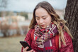 Young woman with Down syndrome walking in street in winter and using smartphone
