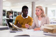 © JackF - Female teacher working with african-american man in university library. High quality photo