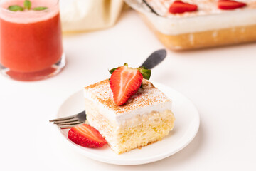 a piece of tres leches cake with a glass of strawberry margarita on a white background