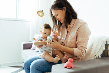 Wall Mural - Mother and her baby son playing at home