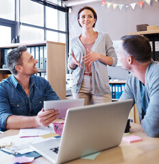 Wall Mural - Preparing for the big presentation. Shot of three coworkers having a meeting in a creative office.