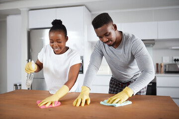 Poster - A little elbow grease makes a home shine. Shot of a young couple cleaning the kitchen counter at home.