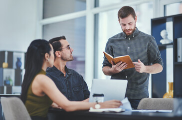 Poster - Guiding his team as the project manager. Shot of a young businessman giving a presentation to his colleagues in an office.