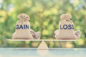 Capital investment gain and loss, financial concept : Gain and loss bags on a basic balance scale, depicts balancing between profit and loss while managing assets e.g bonds, stocks, derivatives, ETFs