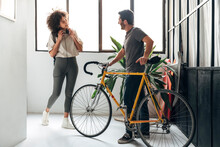 Multiracial Friends Meet At Co Working Office Entrance. Caucasian Man Leaving With A Bike, Woman Arrives At Work.