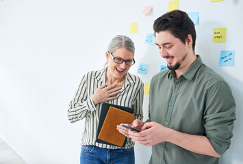 Aufkleber - The client loves the idea we pitched. Shot of two businesspeople using a cellphone together in an office.