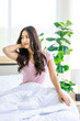 © Bangkok Click Studio - Asian young beautiful happy sleepy female teenager in casual pajama outfit waking up fresh in morning sitting smiling closed eyes under white blanket on bed in bedroom massaging stretching neck