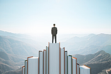 Poster - Back view of businessman standing on book mountain on sky background with mock up place. Education, wisdom and challenge concept.