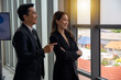 © Paisan - Smiling man and woman standing at meeting room beside windows.