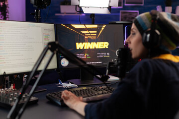 Wall Mural - Adult winning video games on online stream with live chat. Woman streaming gameplay on computer with hmicrophone and headphones. Person broadcasting while she plays video game.