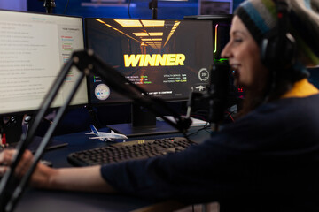 Wall Mural - Woman live streaming online video games on computer. Person broadcasting gameplay, playing live on stream with chat, using monitor and microphone. Streamer wearing headphones to play.