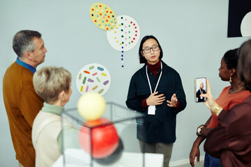 professional gallery worker standing in front of group of tourists speaking about contemporary paint