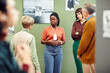 © Seventyfour - Portrait of young African American gallery worker standing in front of visitors discussing black and white photography