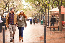Taking A Walk On The Winter Side. Shot Of A Happy Young Couple Walking Through An Urban Area Together.