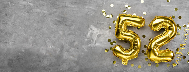 Yellow foil balloon number, number fifty two concrete background. Greeting card with the inscription 52. Anniversary concept. for anniversary, birthday, new year celebration. banner,