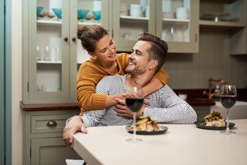 Canvas Print - She sure knows the way to a mans heart. Shot of an affectionate young woman embracing her husband during supper in their kitchen at home.