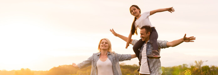 Happy family in the park evening light. The lights of a sun. Mom, dad and baby happy walk at sunset. The concept of a happy family