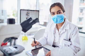 Aufkleber - Just another day in the lab. Portrait of a confident young female scientist wearing a surgical mask and working on a digital tablet while looking at the camera in a laboratory.