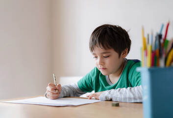 Wall Mural - Happy boy using pencil drawing or sketching on paper, Portrait  kid siting on table doing homework, Child enjoy art and craft activity at home, Education concept