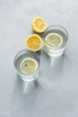 Two glasses of water with lemon slices. Lemon citrus water. Refreshing cold summer drink. Light gray background