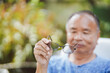 © Oporty786 - Elderly man holding eyeglasses in hand and looking at glasses, selective focus.