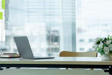 Workplace with notebook laptop Comfortable work table in office windows and city view.