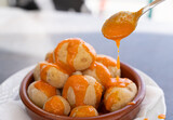 Fototapeta Sypialnia - Spoon pouring spicy mojo sauce on papas arrugadas in clay plate. Traditional wrinkled potatoes snack food from Gran Canaria island, Spain. Healthy diet concept