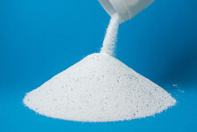 Laundry detergent on a blue background. Washing powder sprinkled on a pile of washing powder. Household chemicals