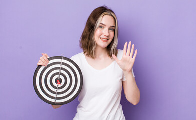 Wall Mural - pretty caucasian woman smiling and looking friendly, showing number five. dart target concept