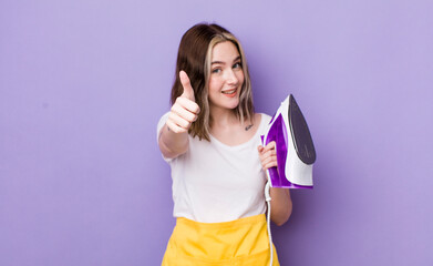 pretty caucasian woman feeling proud,smiling positively with thumbs up. hand iron concept